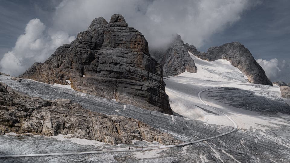 Rocky alpine peaks and a glacier under low clouds