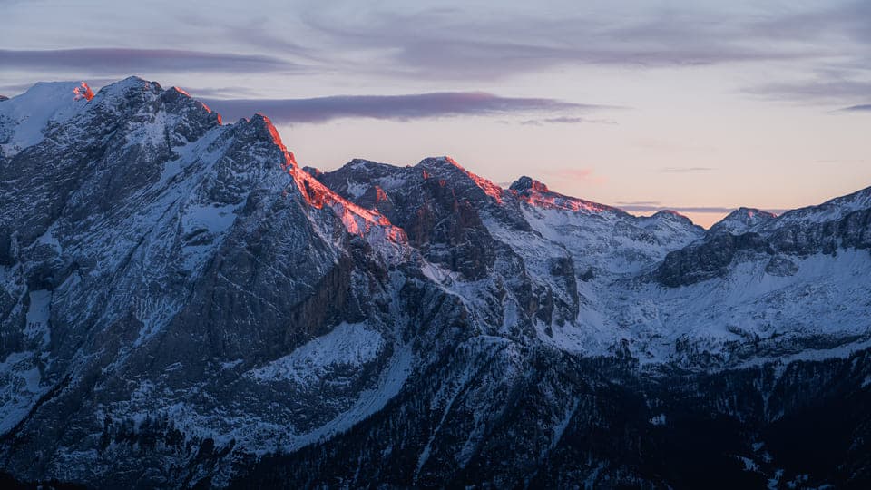 Wide snowy mountain range with pink sunset highlights