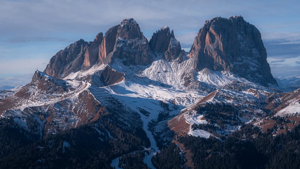 Large rocky mountain massif above snowy forest