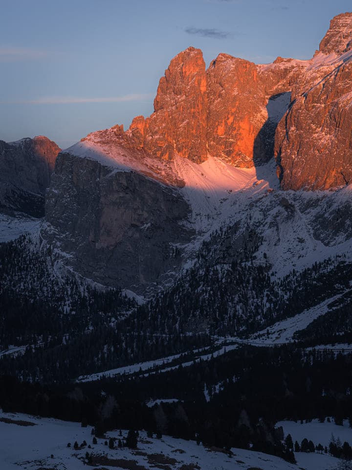 Orange sunset light on rugged snowy cliffs
